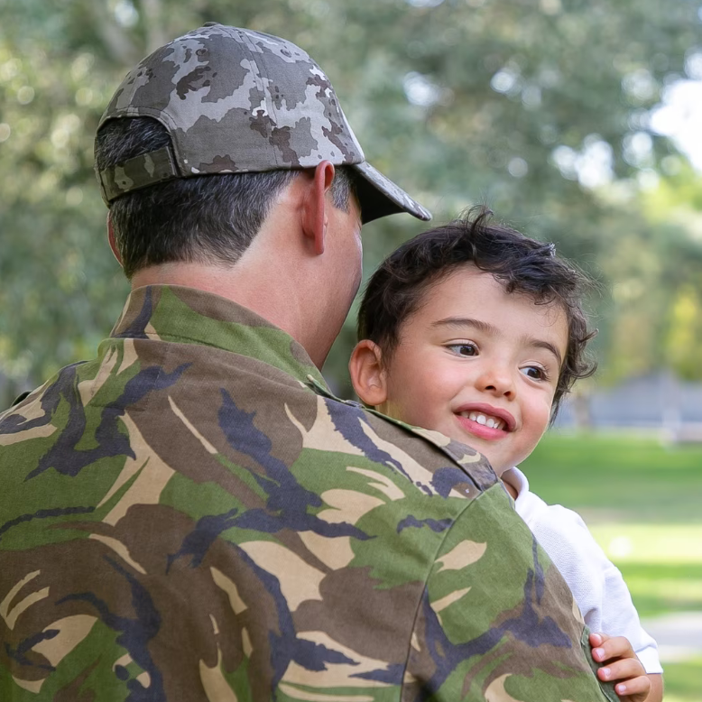 Military individual holding a child over shoulder